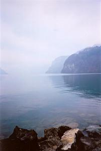 Stones on the shore of Brunnen lake misty hills at horizon