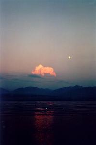 Pink cloud and moon over lake and alps at dusk